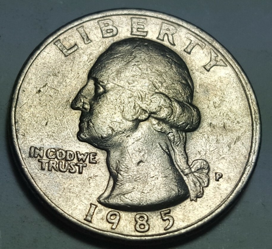 1985 quarter off-center strike error showing crescent-shaped blank area with design shifted to one side